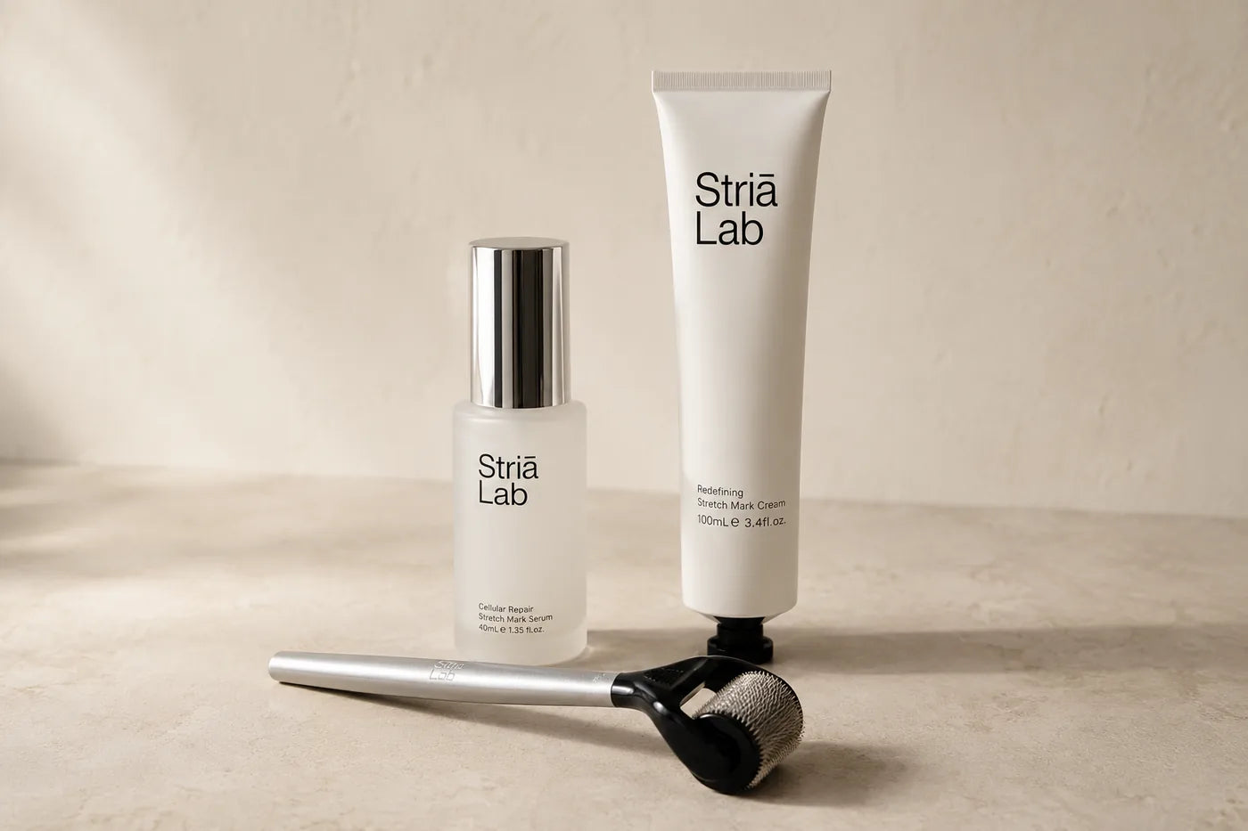 The Striā Lab Cellular Repair Serum bottle, Redefining Cream tube and microneedling tool arranged on a stone surface
