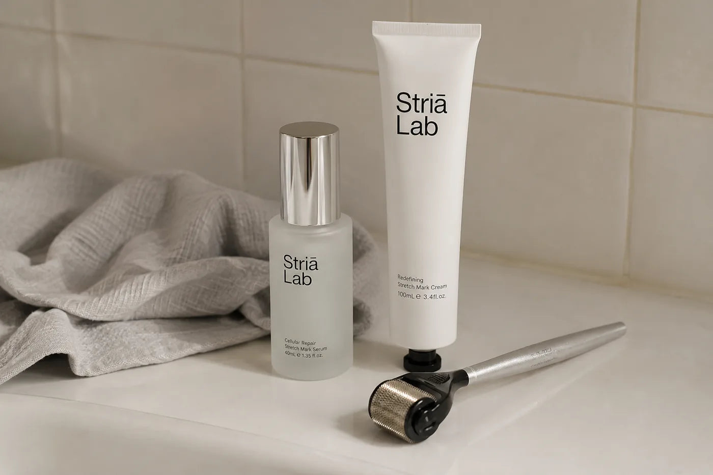 The Striā Lab serum, cream and microneedling tool standing on a bathroom shelf beside a folded cloth